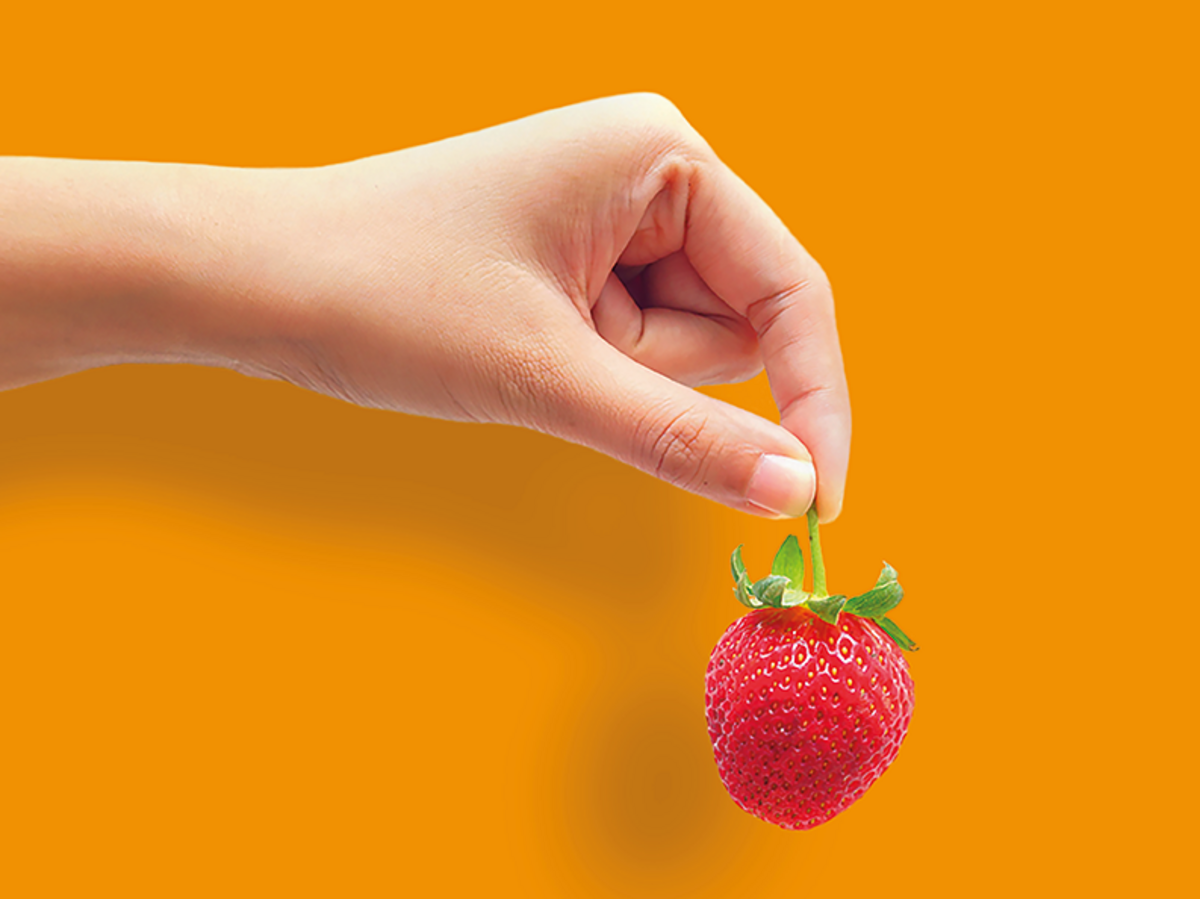 Eine Hand hält eine Erdbeere über einem Text über Krankenversicherungsleistungen und jährliche Einsparungen auf einem orangefarbenen Hintergrund.