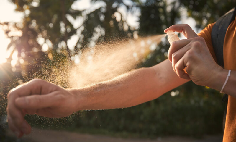 Arm wird mit einem Anti-Mücken-Spray eingesprüht.