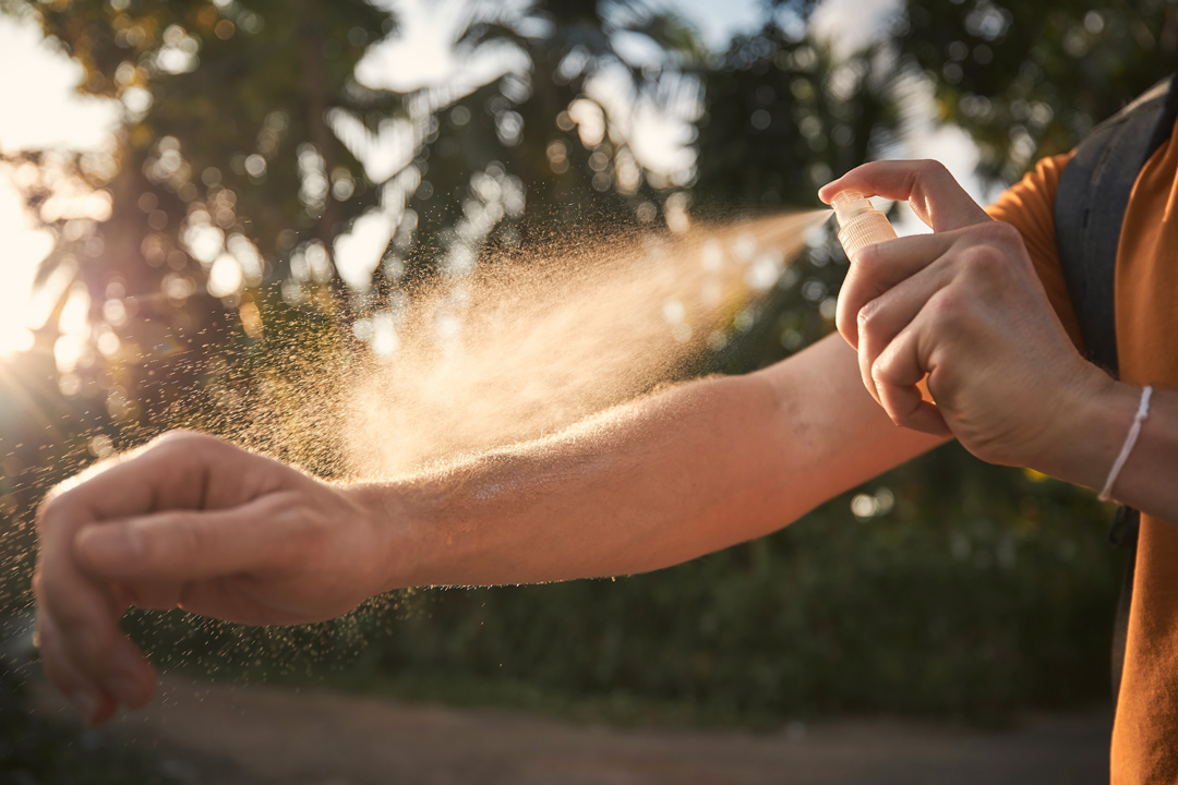 Arm wird mit einem Anti-Mücken-Spray eingesprüht.