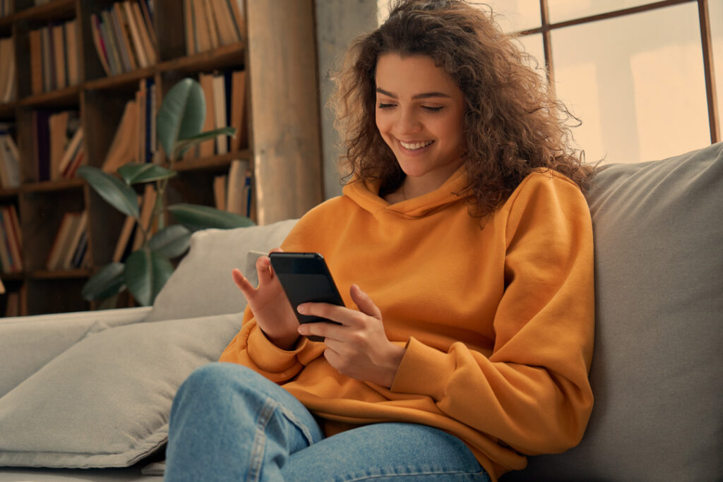 Frau sitzt mit ihrem handy auf dem sofa